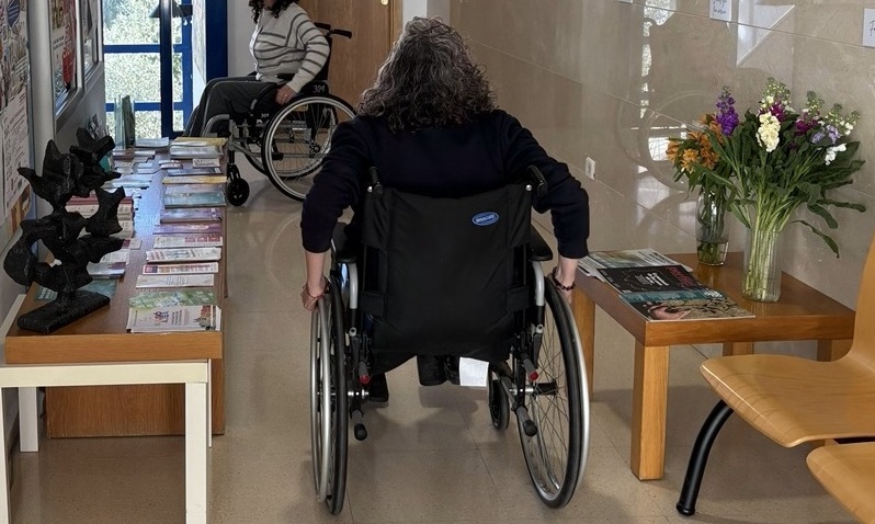 Dos personas realizando un ejercicio de accesibilidad en sillas de ruedas en un edificio público